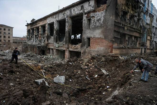 1월 2일 우크라이나 하르키우 중심부에서 러시아 미사일 공격으로 크게 파손된 건물 옆 분화구를 전문가들이 조사하고 있다. (사진=로이터)