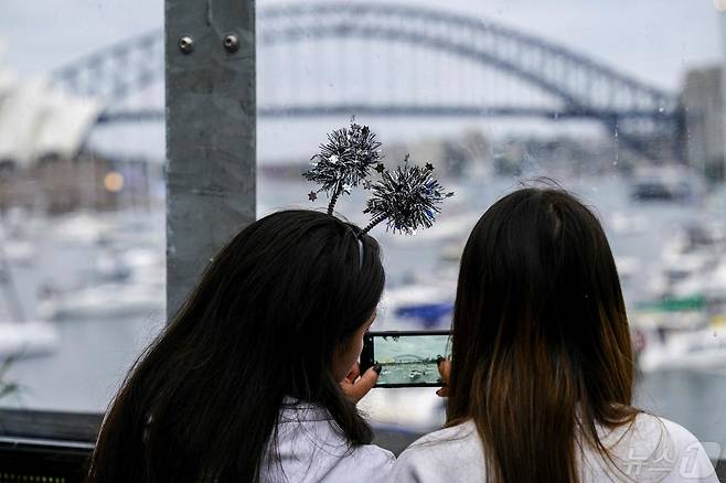 호주 시드니의 시드니 하버 브리지 앞에서 두 여성이 사진을 찍고 있다. 2023.12.31 ⓒ AFP=뉴스1 ⓒ News1 정지윤 기자