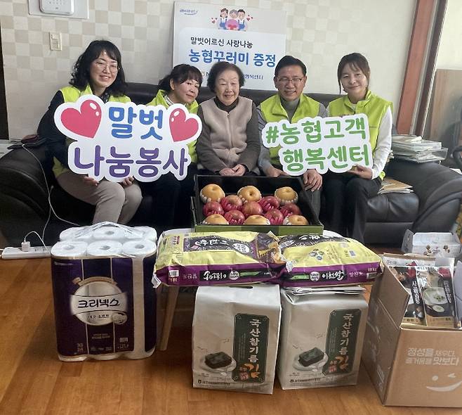 김성훈 농협은행 고객행복센터 센터장(오른쪽에서 두 번째)과 말벗어르신(가운데)을 비롯한 참여자들이 말벗어르신 댁에서 진행한 우리농산물 꾸러미 나눔행사에서 기념촬영을 하고 있다./사진=NH농협은행