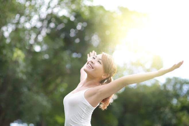 Carefree and free cheering woman in the park. girl raising her arms up smiling happy. asian beauty