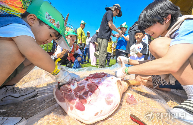 ‘세계구석기 체험마당’의 전곡선사박물관 부스에서 어린이들이 주먹도끼를 사용해 돼지고기를 직접 가르는 체험을 하고 있다. 홍기웅기자