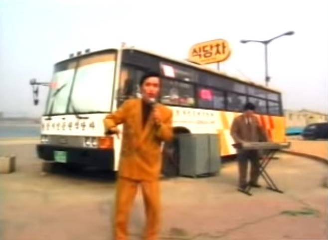 건반 반주에 맞춰 '영맨'을 노래하고 있는 40대의 이박사. 뒤에 뮤직비디오 소품으로 쓰인 식당차가 보인다. /소니뮤직