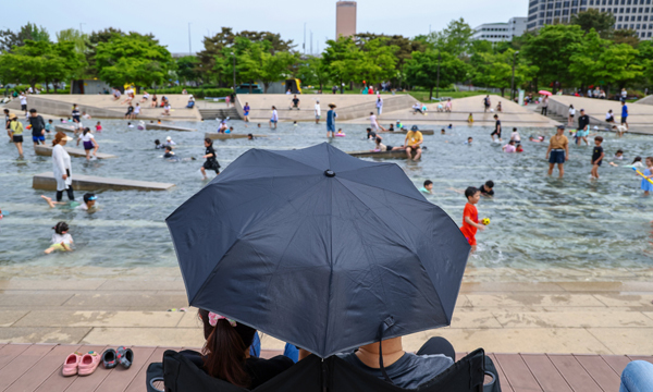 서울 영등포구 여의도한강공원 물빛광장에서 양산을 쓴 시민들이 물놀이하는 시민들을 바라보고 있다. 연합뉴스