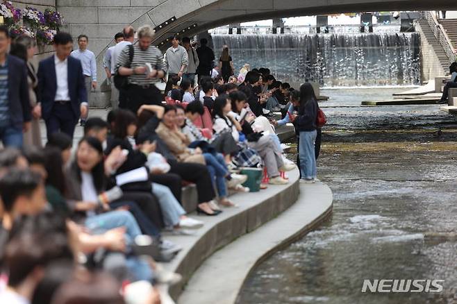 [서울=뉴시스] 정병혁 기자 = 초여름 날씨를 보인 지난달 26일 서울 중구 청계천을 찾은 시민들이 의자에 앉아 휴식을 취하고 있다. 2024.04.26. jhope@newsis.com