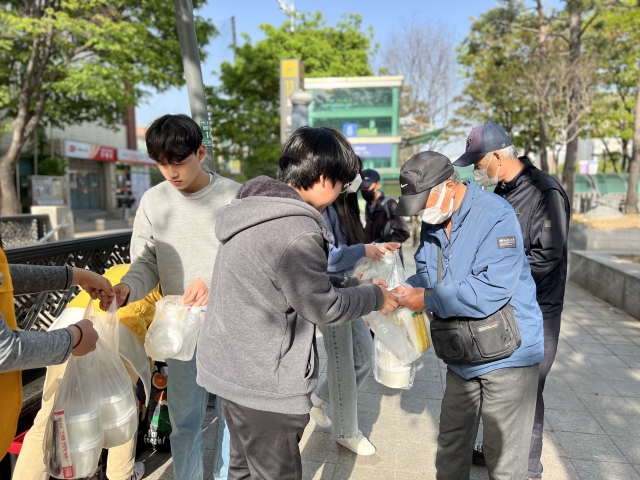 동문교회 중고등부 학생들이 지난 3월 부활주일에 경기도 성남 모란역 인근에서 노숙인에게 도시락을 전달하고 있다. 따밥 제공