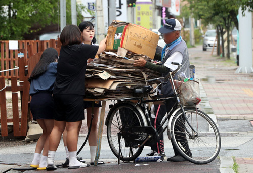 강원 춘천시에서 재활용품 수거 노인의 자전거 위에 있는 폐지가 길바닥에 쏟아지자 길을 지나던 소양고등학교 학생들이 폐지를 주워서 올려주고 있다. [연합]