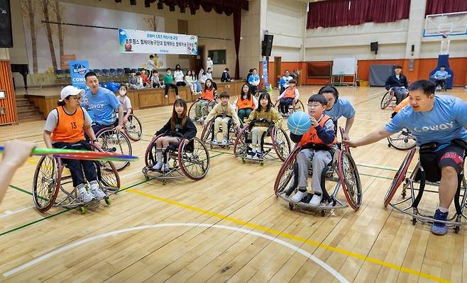 코웨이 블루휠스 휠체어농구단 선수들이 지난 7일 경기 남양주시 평내초등학교에서 학생들을 지도하고 있다. 코웨이 제공
