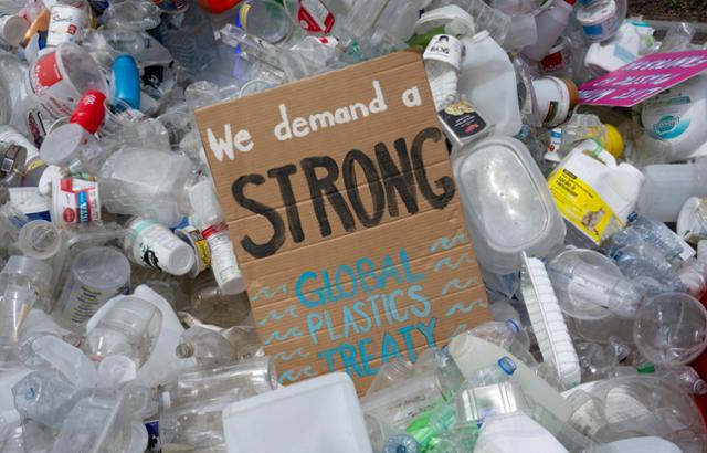 지난달 23일 캐나다 오타와에서 열린 유엔 플라스틱협약 4차 협상위원회 회의장 밖에 쌓인 플라스틱 더미 위에 플라스틱 오염 종식을 위한 강력한 조약 합의를 요구하는 표지판이 놓여 있다. 오타와=AP 뉴시스