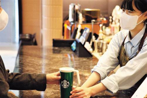 스타벅스 직원이 다회용컵에 담긴 음료를 건네고 있다. [스타벅스 제공]