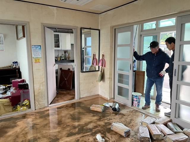 7일 경남 합천군 대양면 양산마을 노인정에 가재도구와 어르신들이 쓰던 배게 등이 흙범벅이 된 채 나뒹굴고 있다. 이 모습을 걱정스럽게 바라보는 주민들.