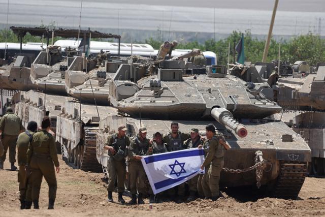 이스라엘 군인들이 9일 이스라엘 남부 가자지구 국경 인근에서 군용 차량에 모여 이스라엘 군기를 들고 있다. EPA 연합뉴스