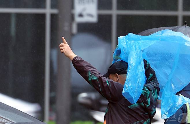 전국에 강풍을 동반한 비가 예고된 11일 오후 서울 종로구 도심을 지나는 한 시민이 우비로 머리를 가린 채 발걸음을 옮기고 있다.  2024.5.11/뉴스1 ⓒ News1 박정호 기자
