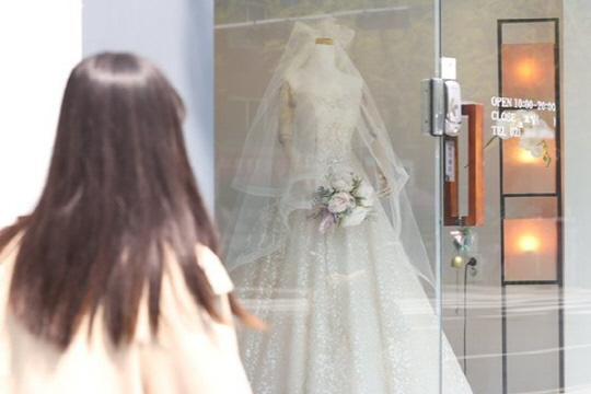 한 여성이 웨딩숍에 비치된 웨딩드레스를 보고 있다.<연합뉴스>