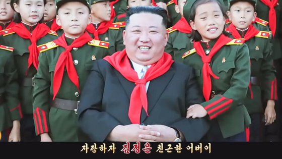 북한이 최근 공개한 선전 가요 '친근한 어버이'의 한 장면. 김정은이 어린 아이들에게 둘러싸여 환히 웃고 있다. 유튜브 '메아리' 캡처.