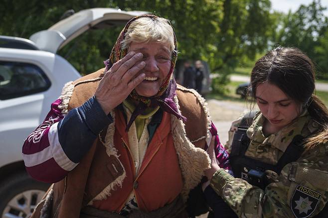 11일(현지시간) 우크라이나 동북부 보우찬스크에서 한 여성이 군인의 도움을 받아 대피하며 눈물을 흘리고 있다. AP연합뉴스