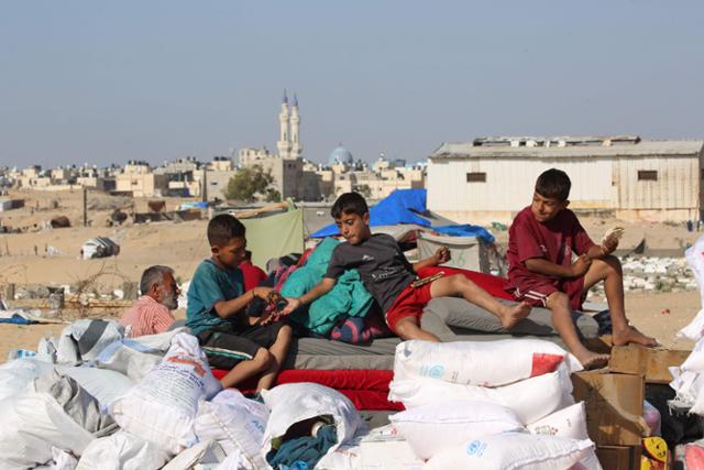 12일 가자지구 최남단 라파에서 이스라엘 공격을 피해 피란 행렬에 합류한 아이들이 피란 차량 위에서 빵을 나눠 먹고 있다. 라파=AFP 연합뉴스
