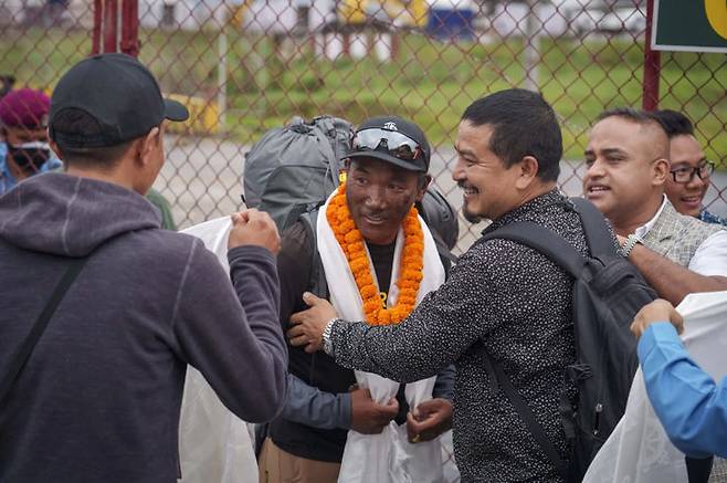 [카드만두 = AP/뉴시스] 올해 5월 12일 에베레스트 등정 신기록을 세운 네팔의 세르파 카미 리타(가운데)가 지난해 5월 23일 28회 등정에 성공한 이틀 뒤 카드만두 공항에 도착해 축하 인사를 받으며 기뻐하고 있다. 2024.05.13  *재판매 및 DB 금지