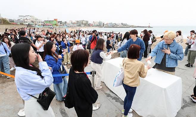 일본인 관광객들이 지난 12일 제주올레 17코스인 이호테우 해수욕장 일대를 걸으면서 플로깅을 하고 슈퍼주니어 D&E에게서 직접 기념품도 받고 있다. 제주도 제공