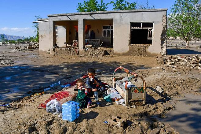 아프가니스탄 북부 바그란주 부르카를 휩쓴 최악의 홍수로 12일 집들이 뼈대만 앙상히 남았다. 놀 곳을 잃은 아이들은 홍수로 쌓인 진흙 토사위에 자그만 카펫을 깔고 앉아있다.   2024.05.13    /AFPBBNews=뉴스1