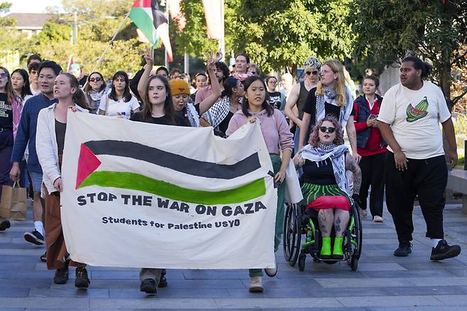호주 시드니에서 24일 팔레스타인을 지지하는 시위대가 ‘가자지구 전쟁을 멈춰라’라고 쓴 현수막을 들고 행진하고 있다.  AP연합뉴스