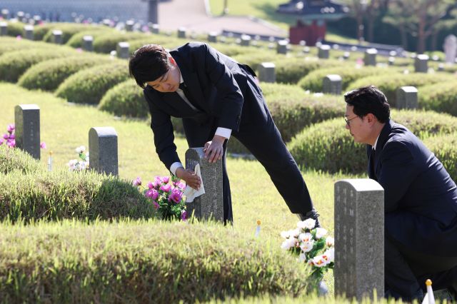 이준석 개혁신당 대표(왼쪽)가 15일 오전 광주 북구 국립 5·18 민주묘지에 있는 한 묘지에 헌화하고 묘비를 닦고 있다. 사진 오른쪽은 천하람 개혁신당 당선인. 연합뉴스