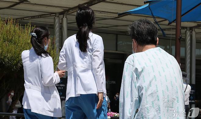 지난 14일 서울 시내의 대형병원에서 한 환자가 휴식을 취하고 있는 가운데, 의료진들이 이동하고 있다. 2024.5.14/뉴스1 ⓒ News1 김성진 기자