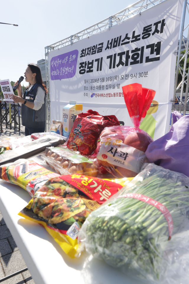 16일 오전 서울 용산 대통령실 인근에서 열린 전국서비스산업노동조합연맹 '최저임금 서비스 노동자 장보기 기자회견'에 한 참석자가 구매한 식료품들이 펼쳐져 있다. 연합뉴스
