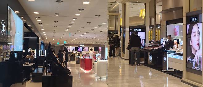 지난 16일 서울 중구에 위치한 백화점 내 명품 브랜드 화장품 매장에서 사람들이 립스틱 제품을 살펴보고 있다(오른쪽). 본인이 찾는 제품을 구매하거나 직원에게 전에 주문한 제품을 찾으러 온 사람들이 매장 앞에서 대기하고 있다. /민영빈 기자