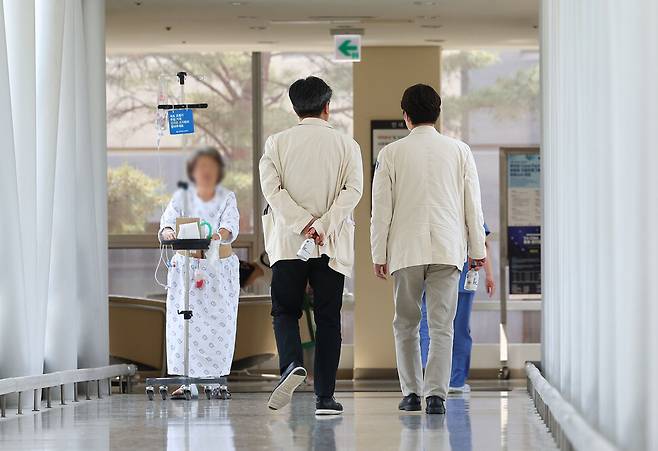 의대 정원 증원 정책의 ‘공공복리’를 인정한 법원 결정이 나온 가운데 17일 서울의 한 대학 병원에서 의료진이 환자 앞을 지나고 있다. 연합뉴스