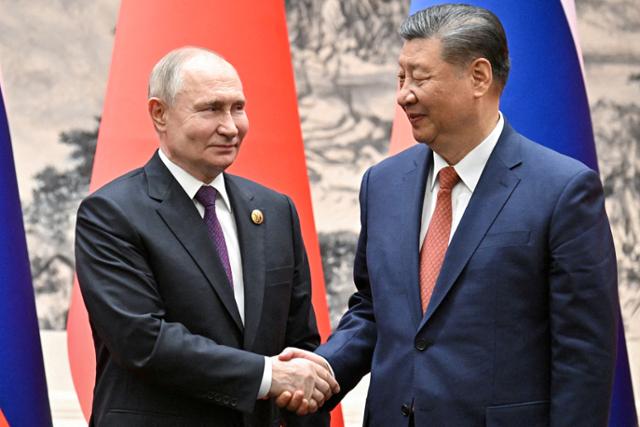 블라디미르 푸틴(왼쪽) 러시아 대통령이 16일 중국 베이징에서 시진핑 중국 국가주석과의 회담 후 악수하고 있다. 베이징=로이터 연합뉴스