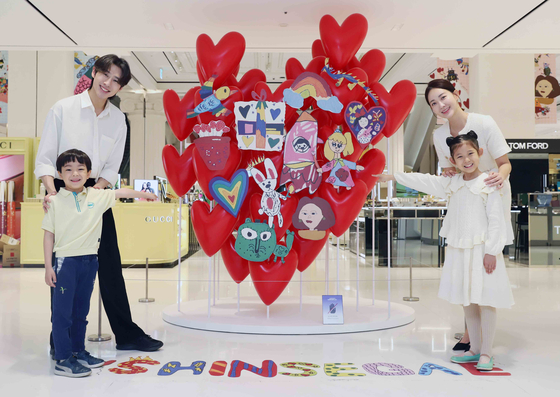 A heart-shaped sculpture features a collage of children's artwork. [SHINSEGAE DEPARTMENT STORE]