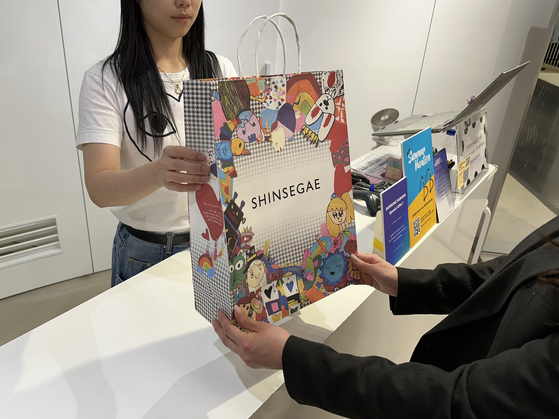 Customers who purchase products from selected brands at Shinsegae receive a shopping bag decorated with children's drawings as part of the campaign, The Greatest Gift of All. [SEO JI-EUN]