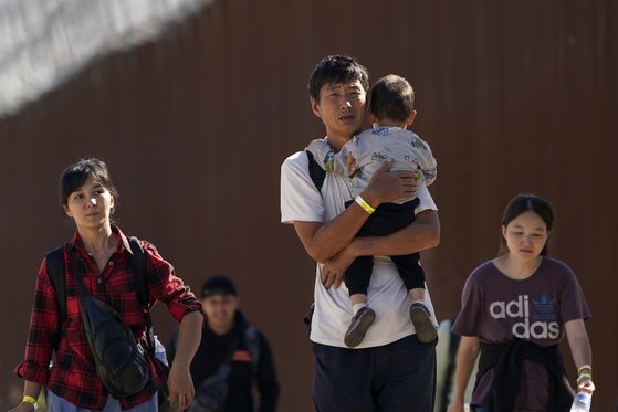 2023년 10월 24일 중국인 가족 등이 미국에 망명 신청을 하기 위해 멕시코 국경을 넘은 후 장벽을 따라 걷는 모습. AP=연합뉴스