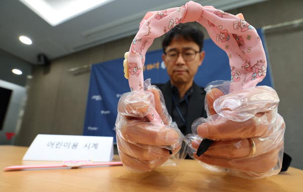 지난 16일 서울시 직원이 조사 결과 인체발암 가능 물질이 검출된 해외직구 어린이용 머리띠와 시계를 들어 보이고 있다. 연합뉴스