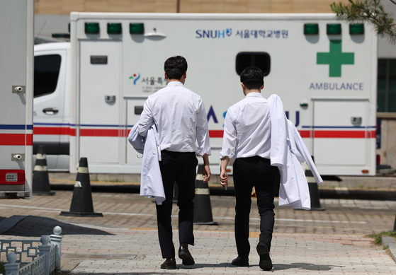 Two medical professionals holding their white gowns walk inside a compound of a general hospital in downtown Seoul on Monday. [NEWS1]