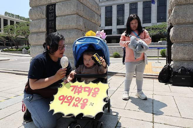 한국 정부의 기후 변화 대응이 헌법에 합치하는지를 묻는 기후소송 두 번째 공개 변론이 열린 21일 오후 서울 종로구 헌법재판소 앞에서 기후소송 원고 단체의 기자회견이 열려 한 어린이가 유모차 앞에 손팻말을 붙인 채 참석하고 있다. 백소아 기자