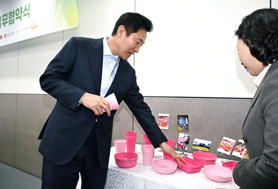 Seoul Mayor Oh Se-hoon looks at reusable containers during the 'Multiuse Plastic Food Tray Program' partnership agreement ceremony at Seoul City Hall on April 12. [YONHAP]