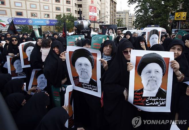 숨진 라이시 대통령 애도하는 이란인들 (테헤란 EPA=연합뉴스) 20일(현지시간) 헬기 추락 사고로 숨진 에브라힘 라이시 이란 대통령 애도식이 열린 테헤란에서 여성들이 라이시 대통령의 포스터를 들고 있다. 라이시 대통령을 포함한 이란 고위 각료들은 전날 아제르바이잔 국경 지대에서 탑승한 헬기가 산악 지대에 추락하면서 사망했다. 2024.05.21 passion@yna.co.kr