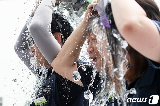 민주노총 전국건설노동조합 조합원들이 서울 용산구 대통령실 앞에서 열린 폭염대책 마련 촉구 기자회견에서 안전모에 얼음물을 담아 붓는 퍼포먼스를 펼치고 있다.  ⓒ News1 유승관 기자