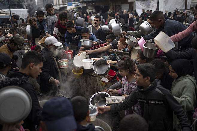 21일(현지시각) 팔레스타인 주민들이 가자 남부 라파흐에서 식량을 받기 위해 줄을 서 있다. AP 연합뉴스