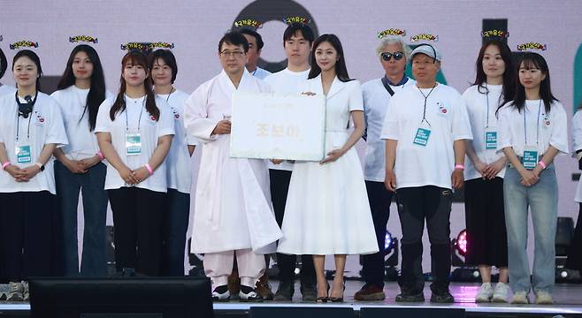 Actress Cho Bo-ah (left in the front row) holds a letter of appointment naming her as the new brand ambassador, with the Head of Cultural Heritage Service Cho Eung-chon (right) at Gyeongbokgung in central Seoul on Tuesday. (Yonhap)