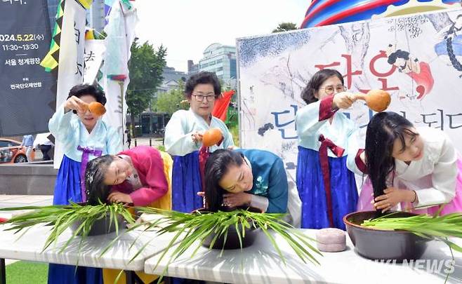 22일 오전 서울 중구 청계광장에서 전국단오제연합 주최로 열린 '단오, 단 하나가 되다' 행사에서 참가자들이 창포물 머리감기 시연을 보이고 있다.