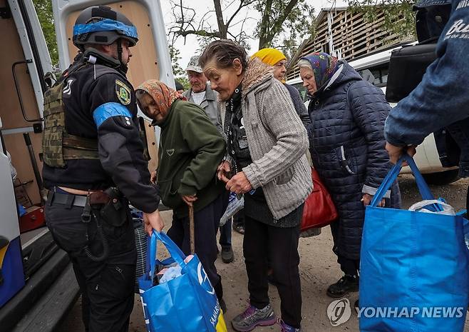 17일(현지시간) 우크라이나 하르키우 보우찬스크 지역에서 경찰관들이 지역 주민들 대피를 돕고 있다. [로이터=연합뉴스 자료사진. 재판매 및 DB 금지]