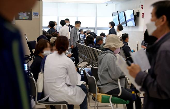 의정 갈등이 계속되는 가운데 22일 서울의 한 대학병원 진료실 앞에서 의료진이 대기 중인 환자에게 다가가 진료를 보고 있다./연합뉴스