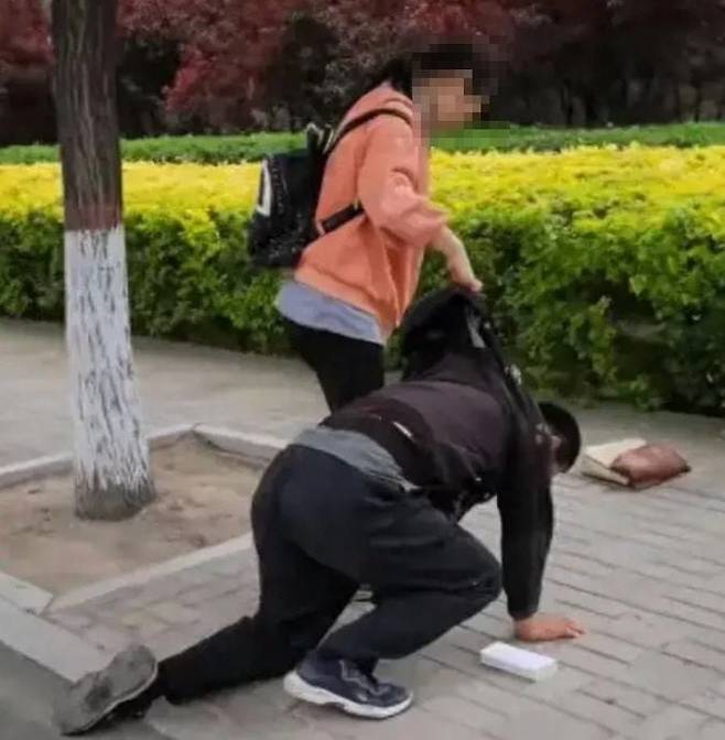 지난 4일 중국 산시성 타이위안에서 한 아버지가 자신의 10대 딸에게 아이폰을 사 줄 형편이 안된다며 무릎을 꿇고 사과 하는 모습./바이두