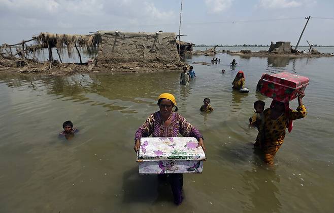2022년 9월 대규모 홍수가 발생한 파키스탄 남부 신드주에서 주민들이 가재도구 등을 들고 대피하고 있다. 신드주/AP 연합뉴스