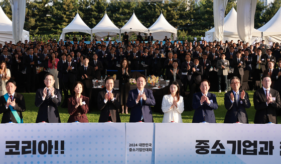 President Yoon Suk Yeol, center, business executives and government officials applaud a performance given at the 35th conference of small and medium-sized enterprises, held at the front lawn of the presidential office in Yongsan District, central Seoul, on Thursday. From second left are Samsung Electronics Executive Chairman Lee Jae-yong; Minister of SMEs and Startups Oh Young-joo; Korea Federation of Small and Medium Business Chairman Kim Ki-mun, third from right; Minister of Foreign Affairs Cho Tae-yul, second from right; and LG Chairman Koo Kwang-mo, far right. [JOINT PRESS CORPS]