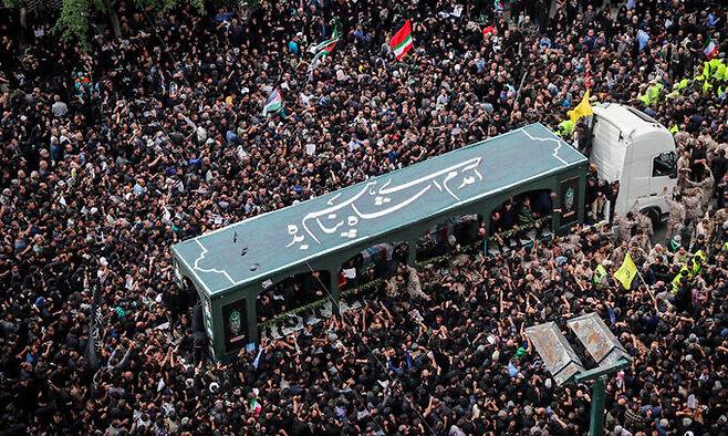 23일(현지시간) 이슬람 시아파 성지 이란 마슈하드에서 에브라힘 라이시 대통령 시신을 실은 운구차량이 인파를 뚫고 매장지로 향하고 있다. IRNA 통신 제공, 연합뉴스