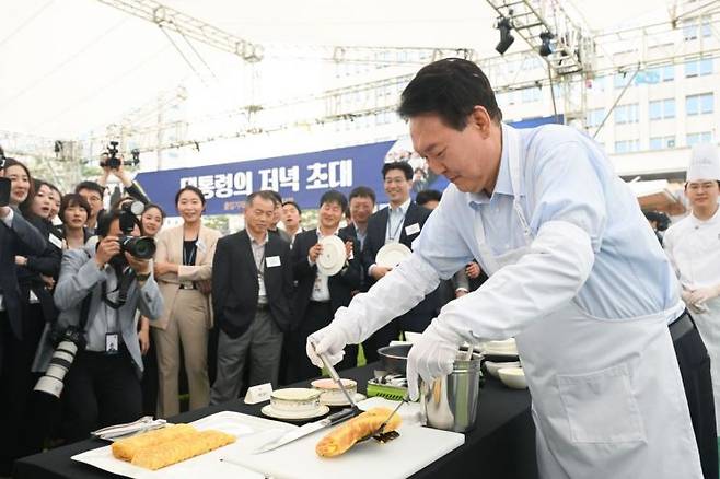 윤석열 대통령이 24일 서울 용산 대통령실 청사 잔디마당에서 열린 '대통령의 저녁 초대' 출입기자단 초청 만찬 간담회에서 계란말이를 만들고 있다. 윤 대통령은 "후보 시절 계란말이와 김치찌개를 대접하겠다고 약속했는데 벌써 2년이 지나도록 못했다"면서 "오늘 음료수와 음식을 맛있게 즐겨주시기 바라겠다"고 웃었다. [이미지출처=연합뉴스]