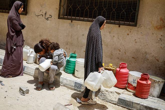 5월22일 가자지구 남부 칸유니스에서 주민들이 물을 구하기 위해 차례를 기다리고 있다. REUTERS 연합뉴스